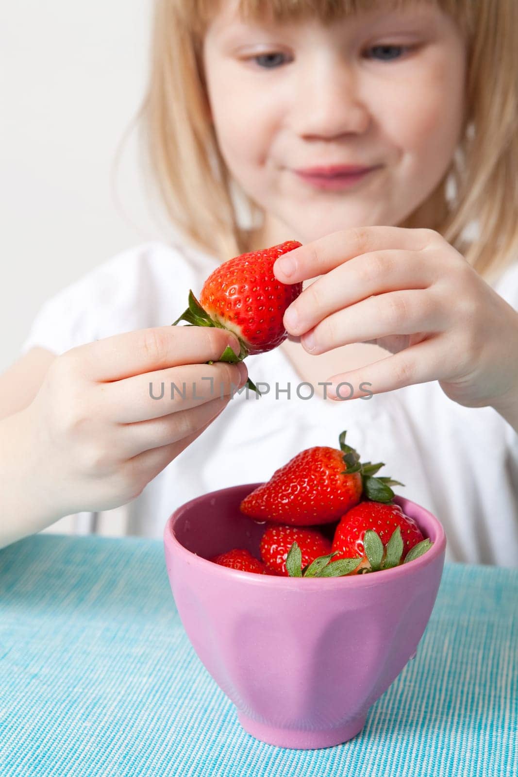 Little girl with a bowl of delicious strawberries