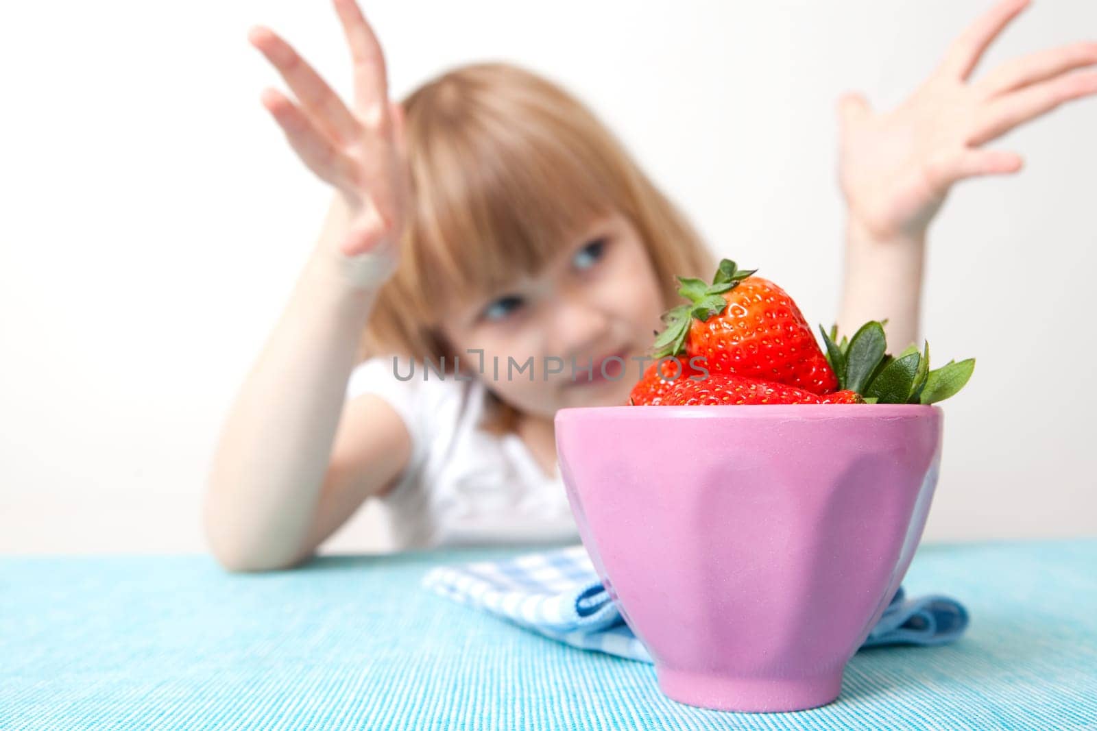 Little girl with a bowl of delicious strawberries