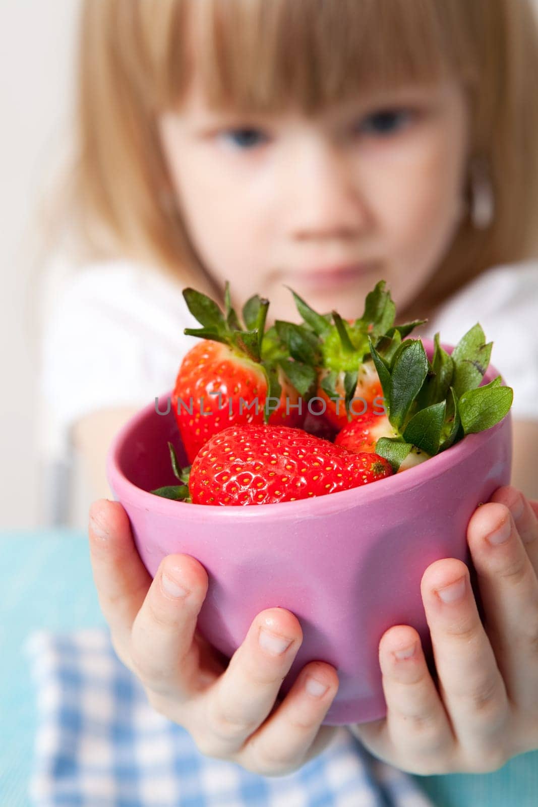 Little girl with a bowl of delicious strawberries