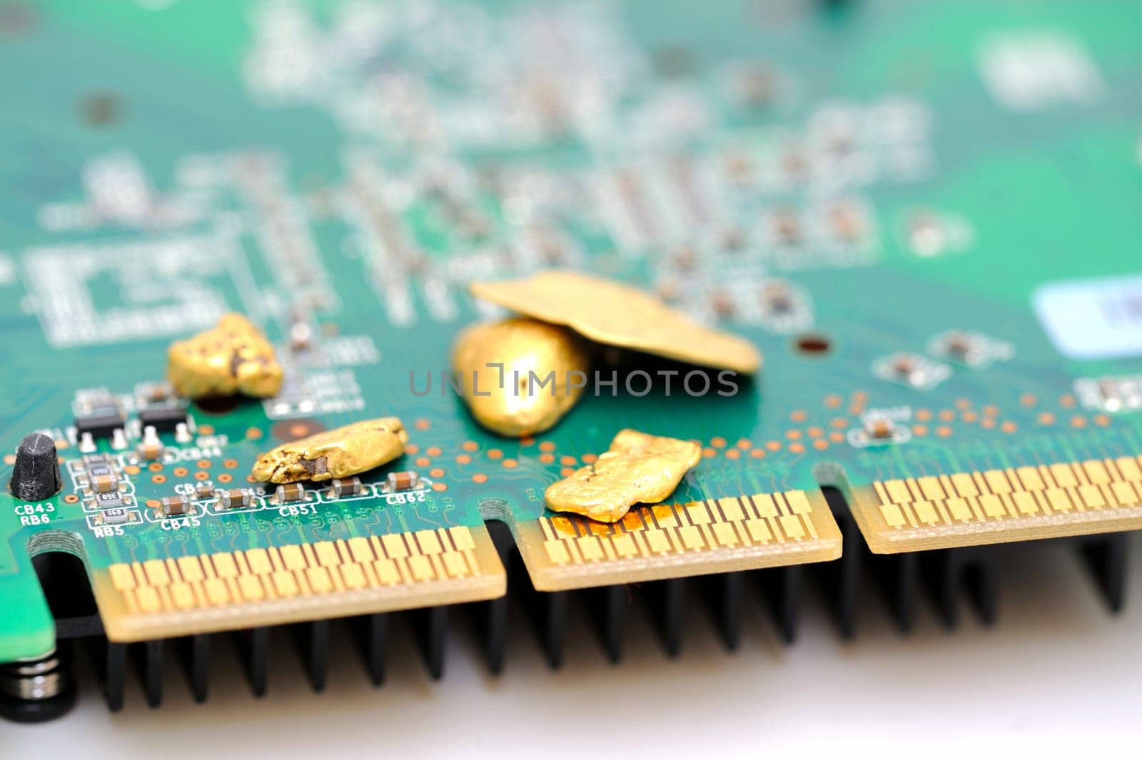 Gold is an important part of modern technology. raw gold nuggets on top of a finished circuit board with gold plated connections