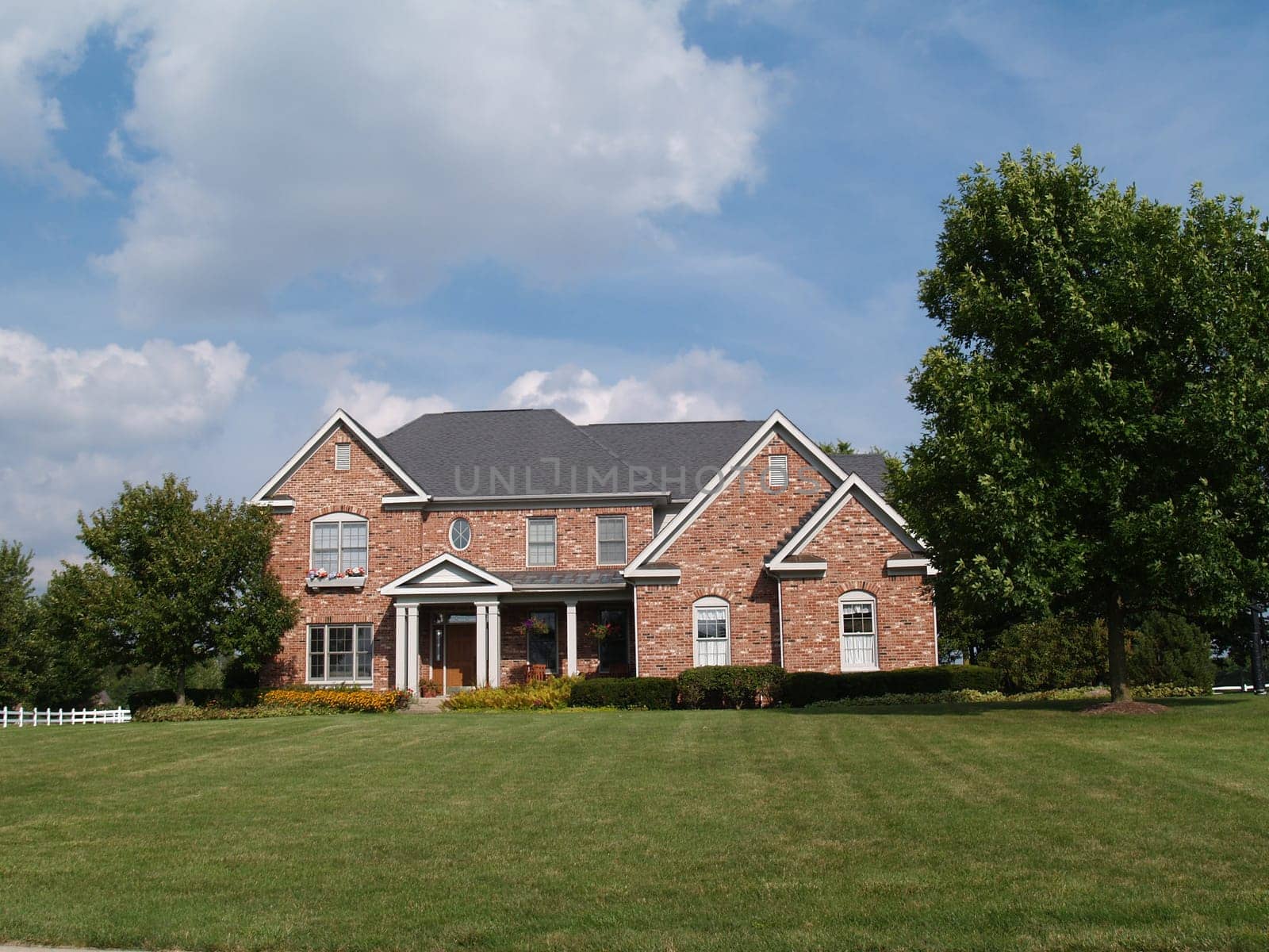 Two story large brick residential home with flower box.