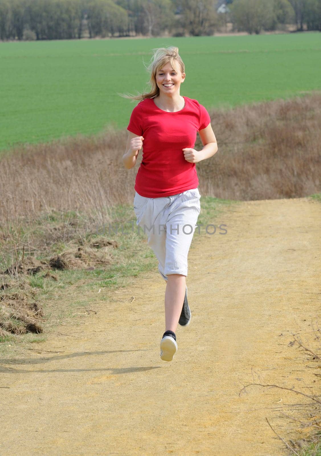 Young woman jogging on a dirt road