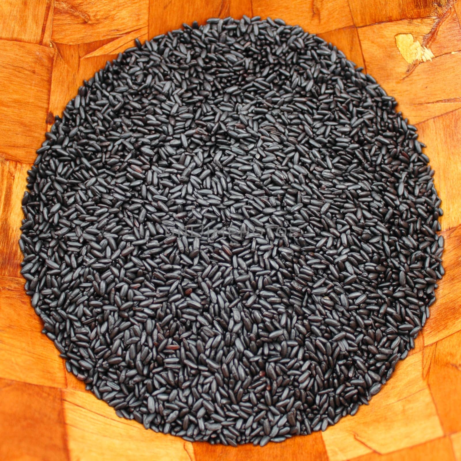Organic black purple rice shaped into a circle in a wood bowl, square photo.
