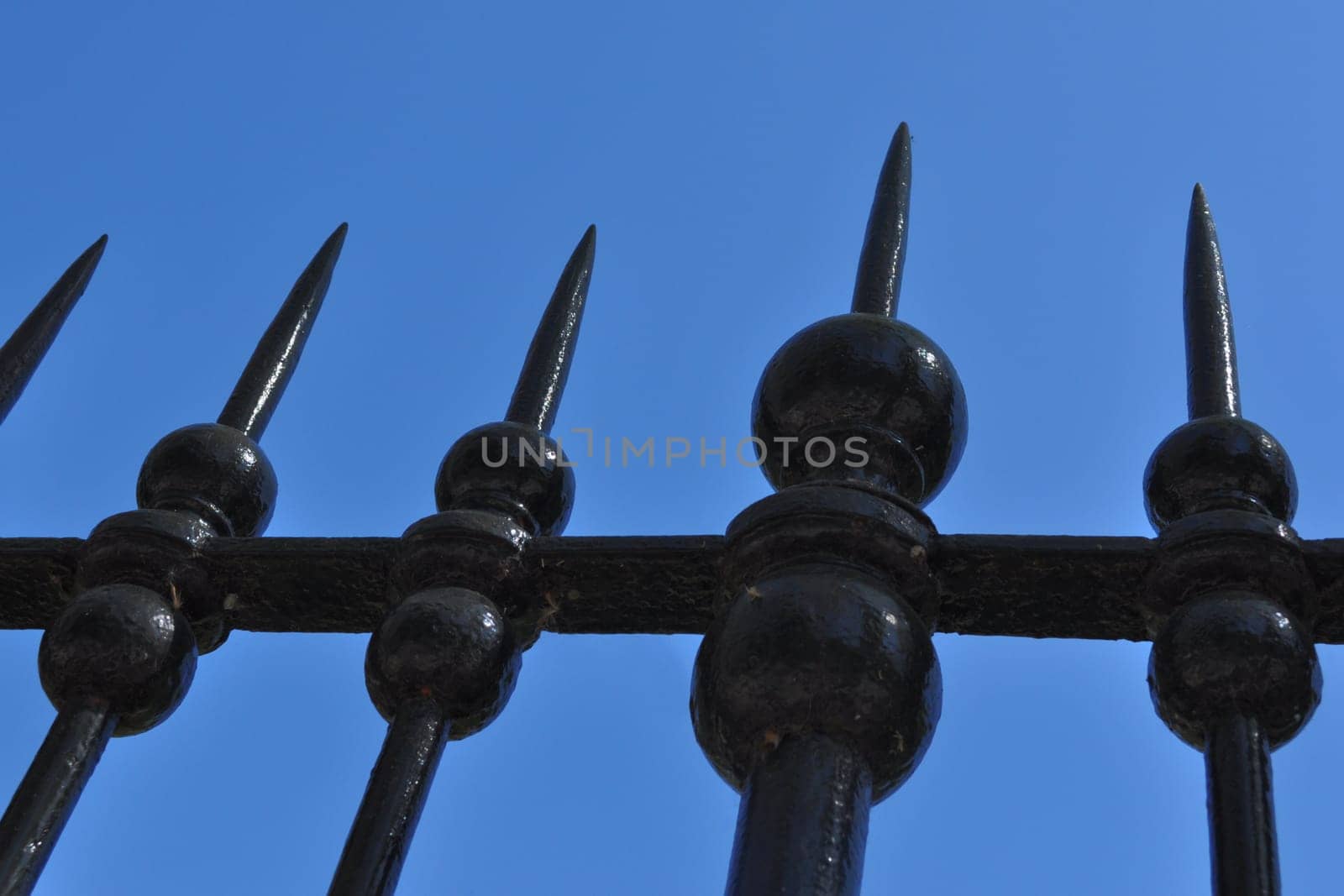 An iron metal fence over blue sky