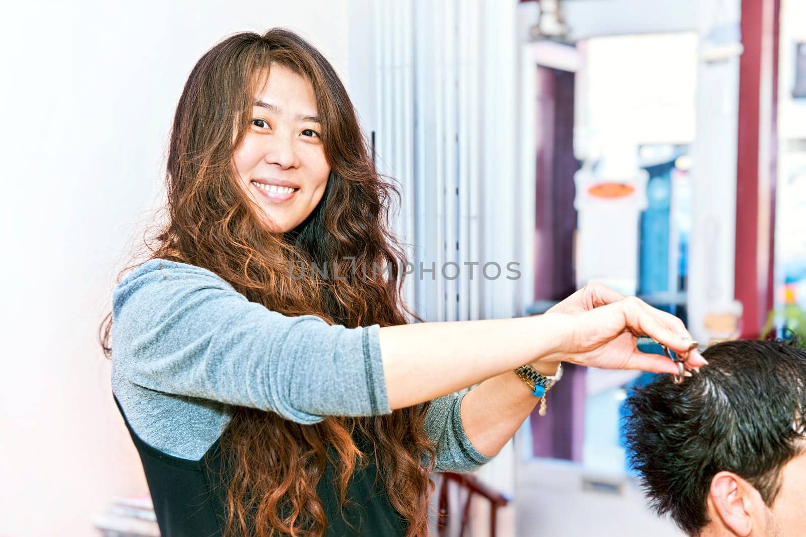 Happy hairstylist cutting hair in her salon