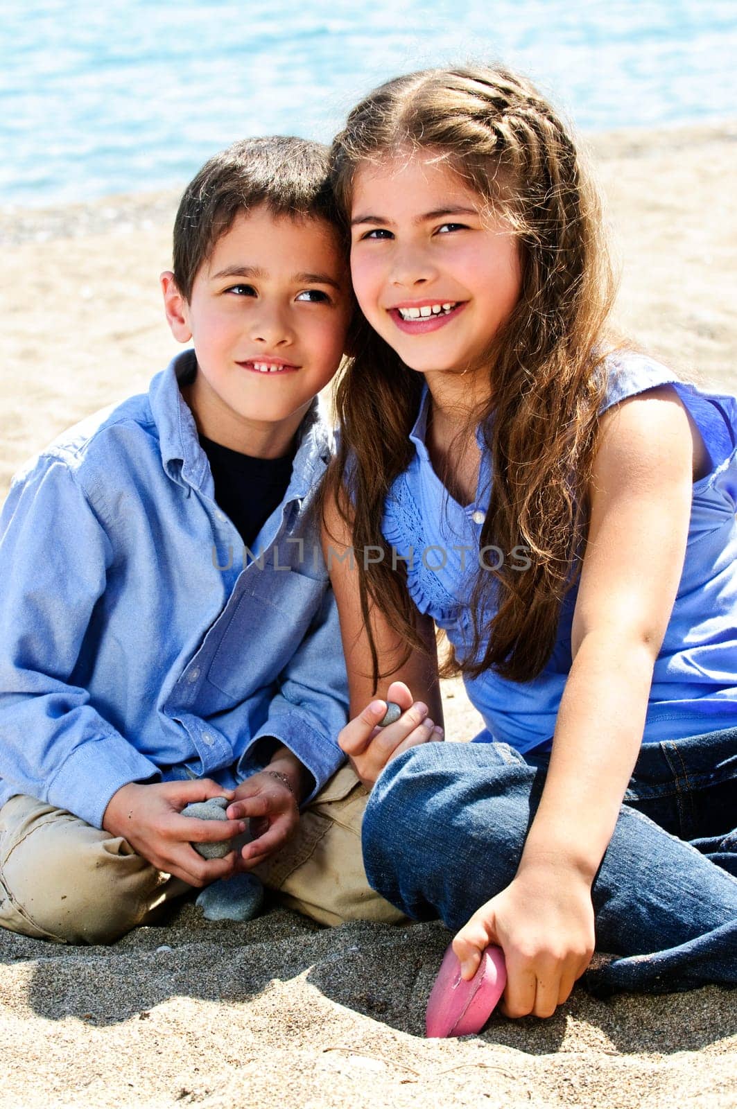 Portrait of brother and sister sitting on sand at the beach