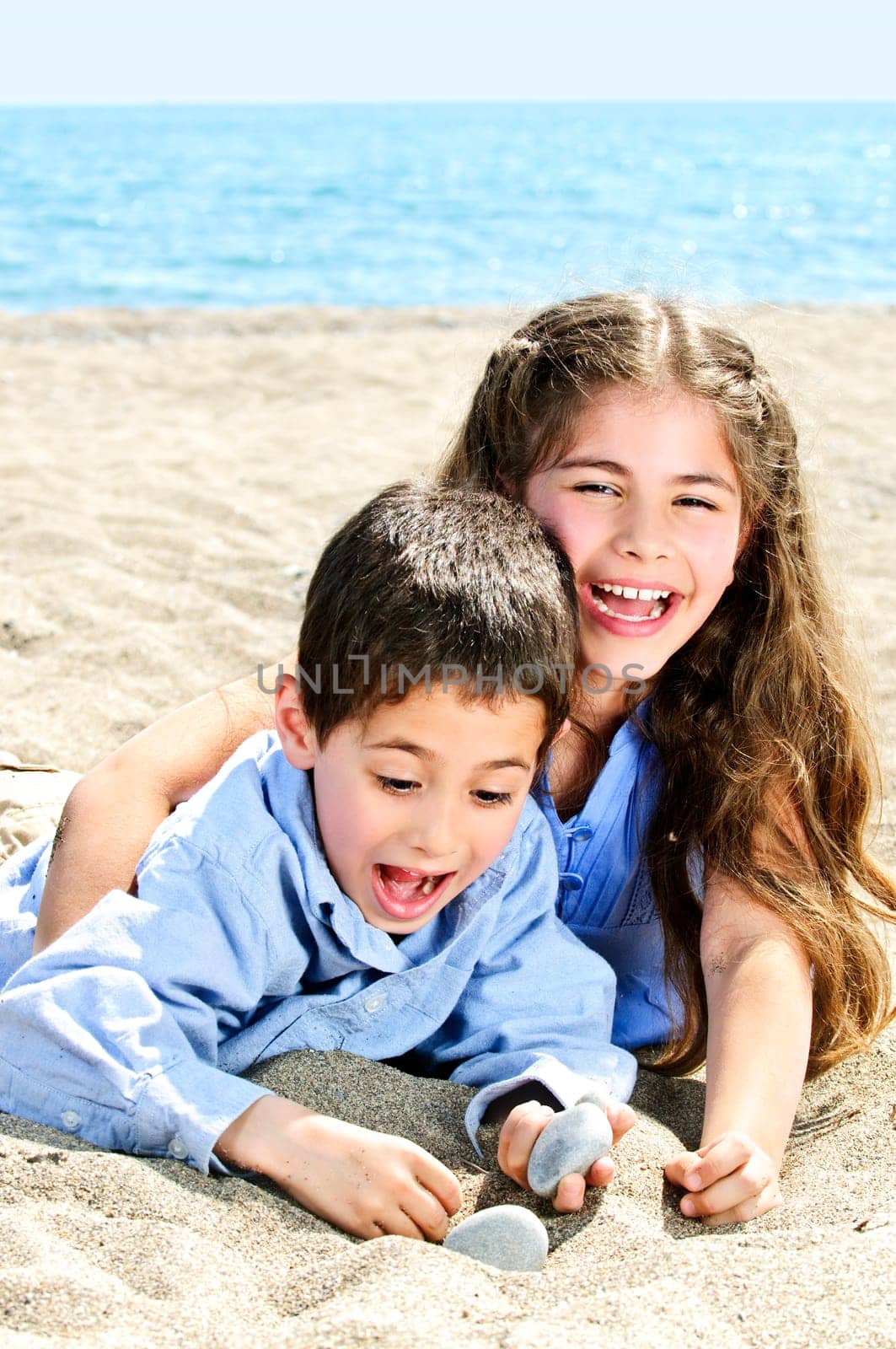 Portrait of brother and sister playing in sand at the beach