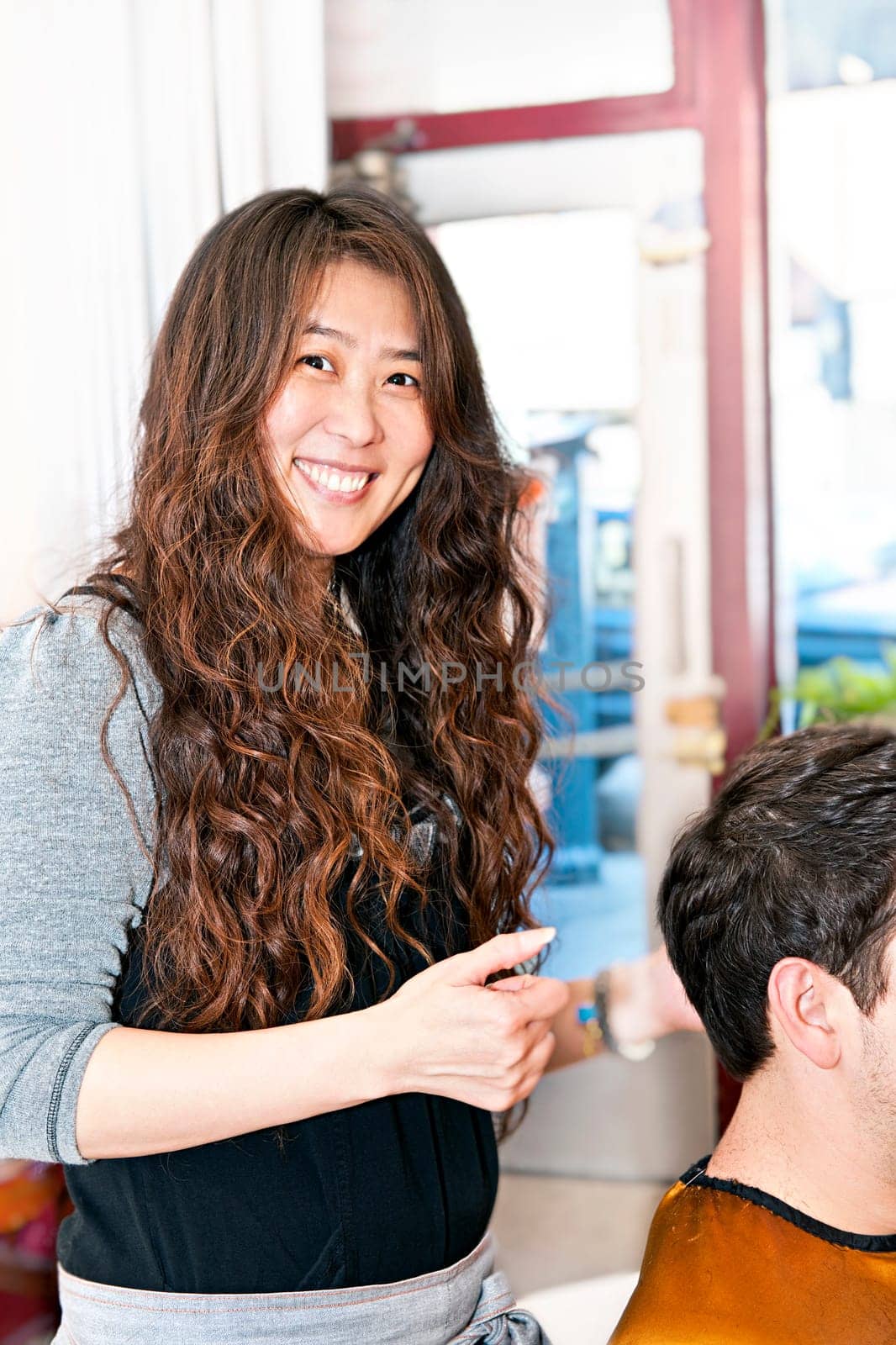 Smiling hairdresser cutting hair in her salon