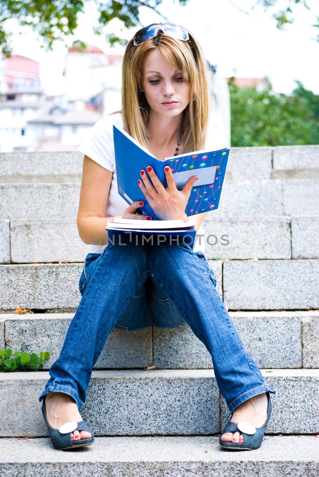young beautiful woman holding books and reading on stairs