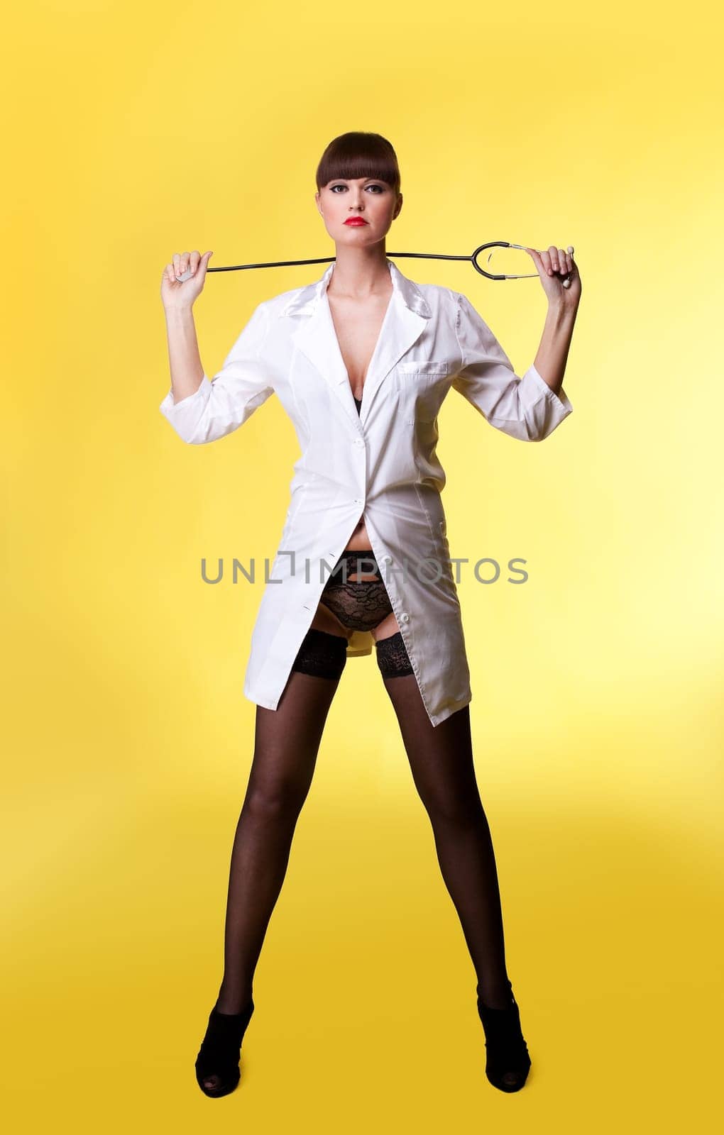 Attractive woman in sexy nurse suit and lingerie with stethoscope on yellow - ppinup style