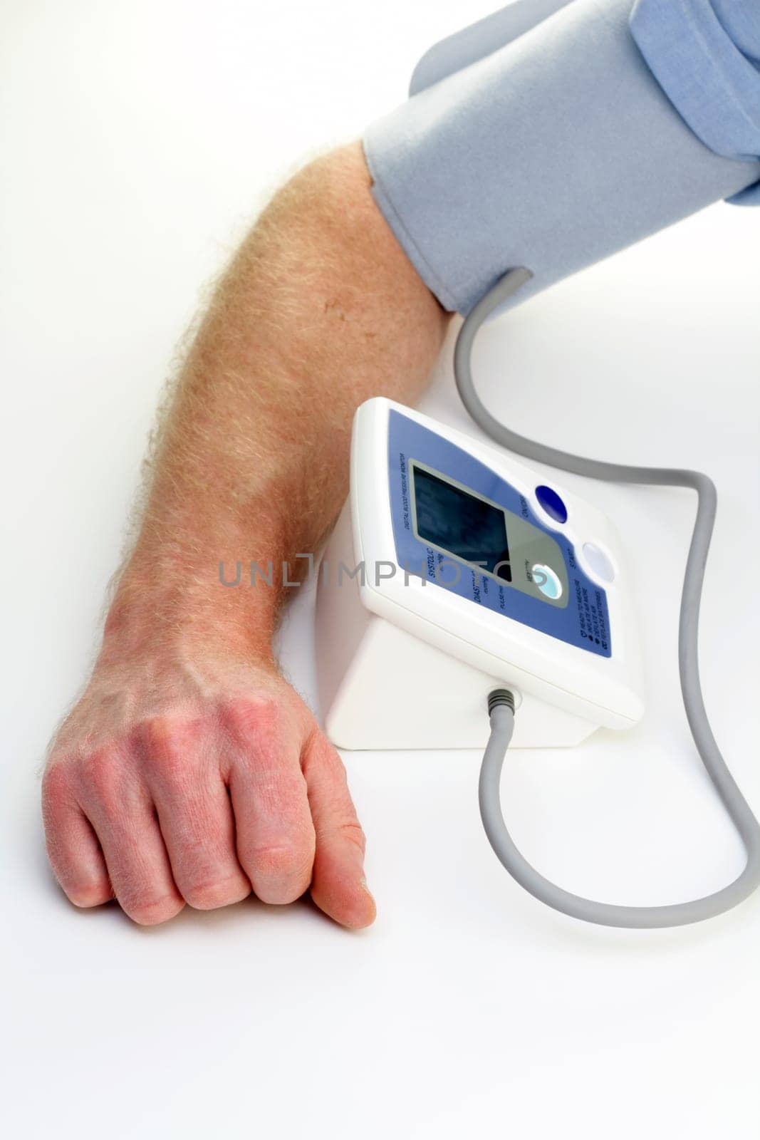 Male arm seen checking own blood pressure with an automatic monitor at home.