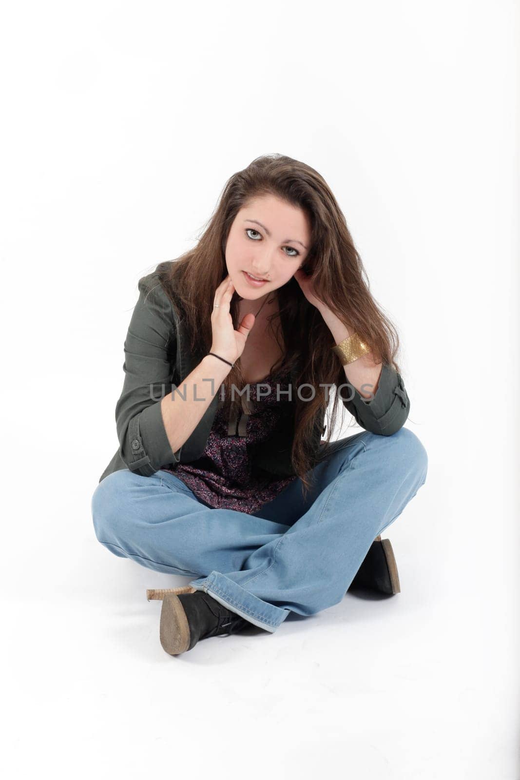 Young pretty teenage girl brunette in studio with long hair looking at the camera