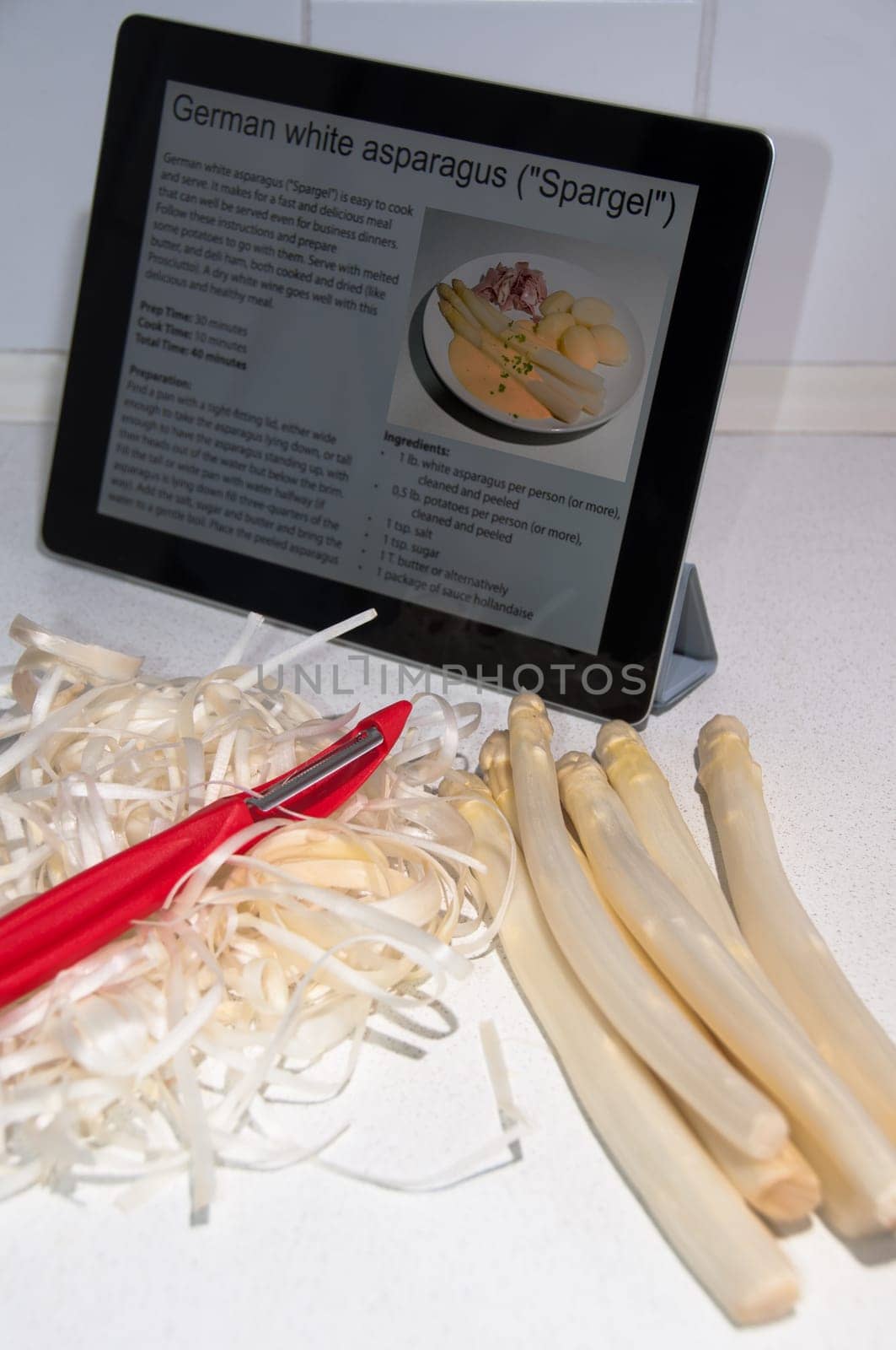 Modern Cooking with Digital Tablet PC displaying recipe of white asparagus
