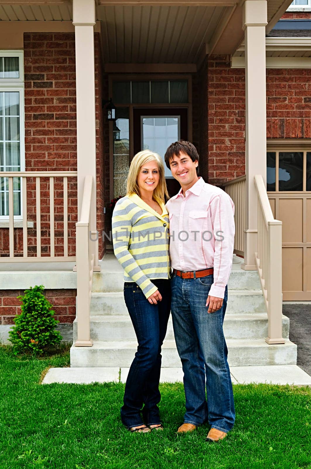 Young happy couple standing in front of house