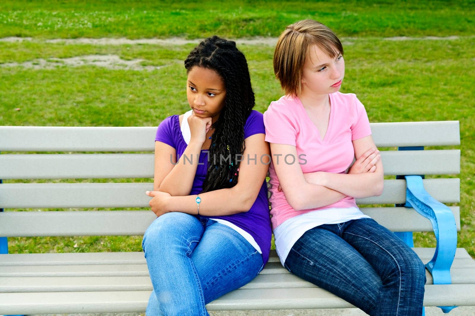 Two bored teenage girls sitting on bench
