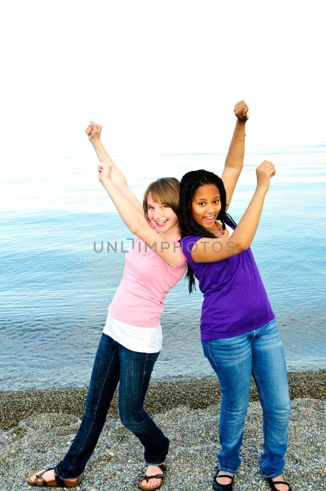 Portrait of two teenage girl friends raising arms