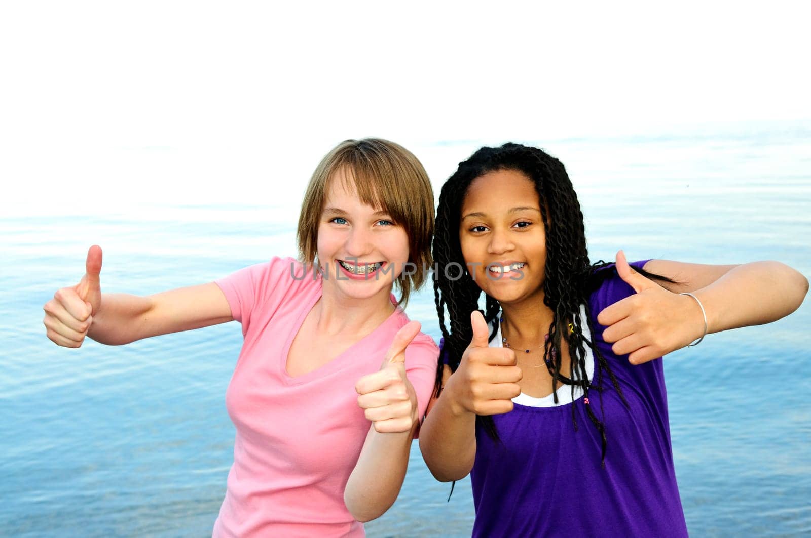 Portrait of two teenage girl friends showing thumbs up