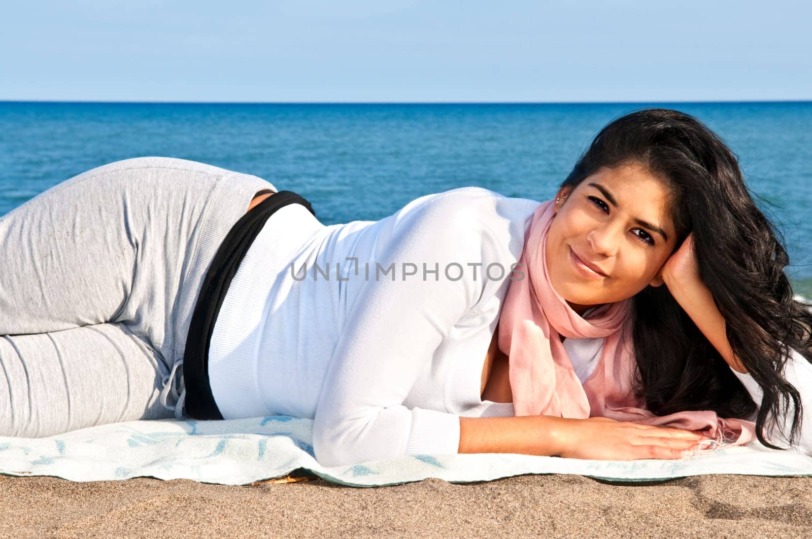 Portrait of beautiful smiling native american girl laying at beach
