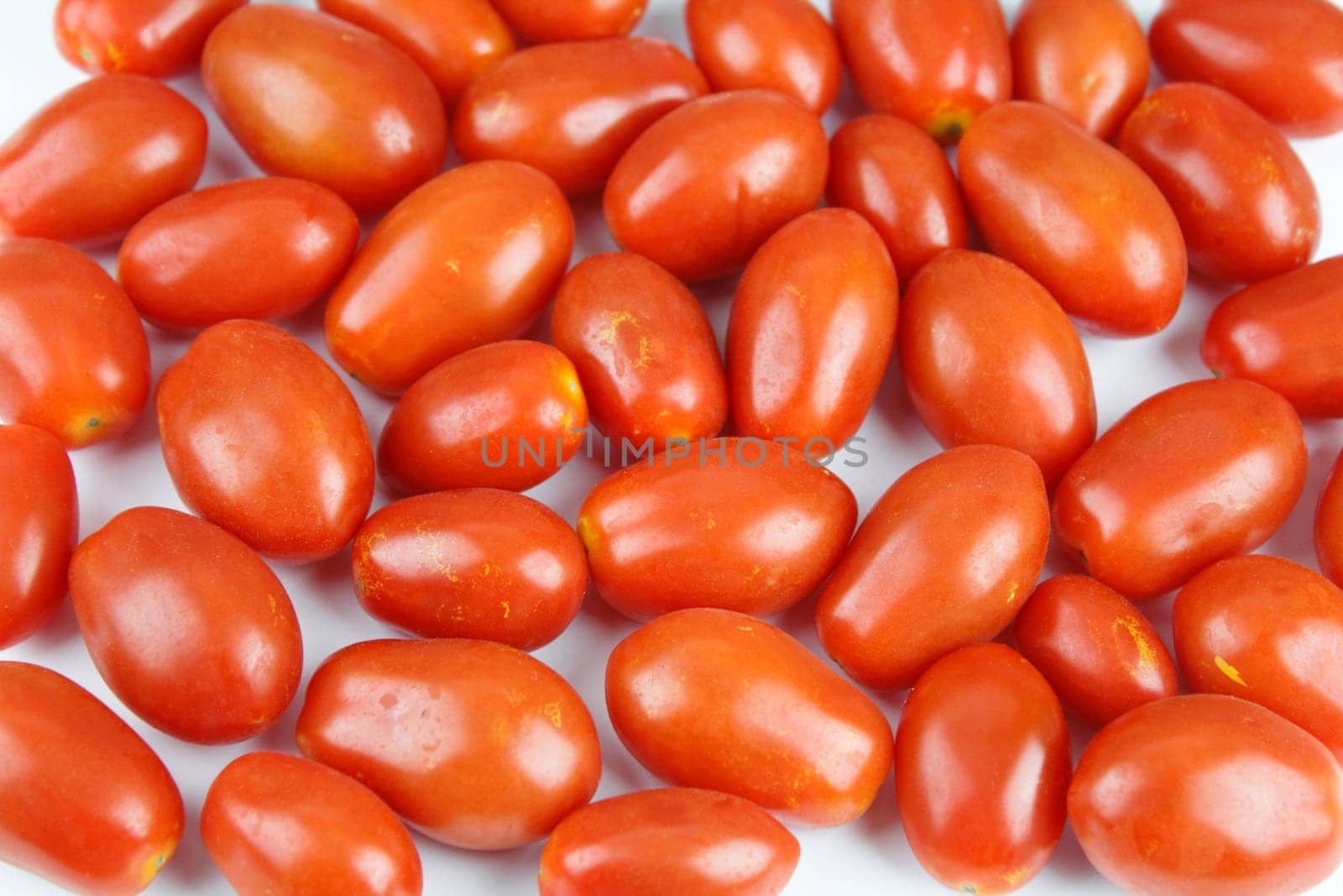 Small red organic tomatoes on a white background.