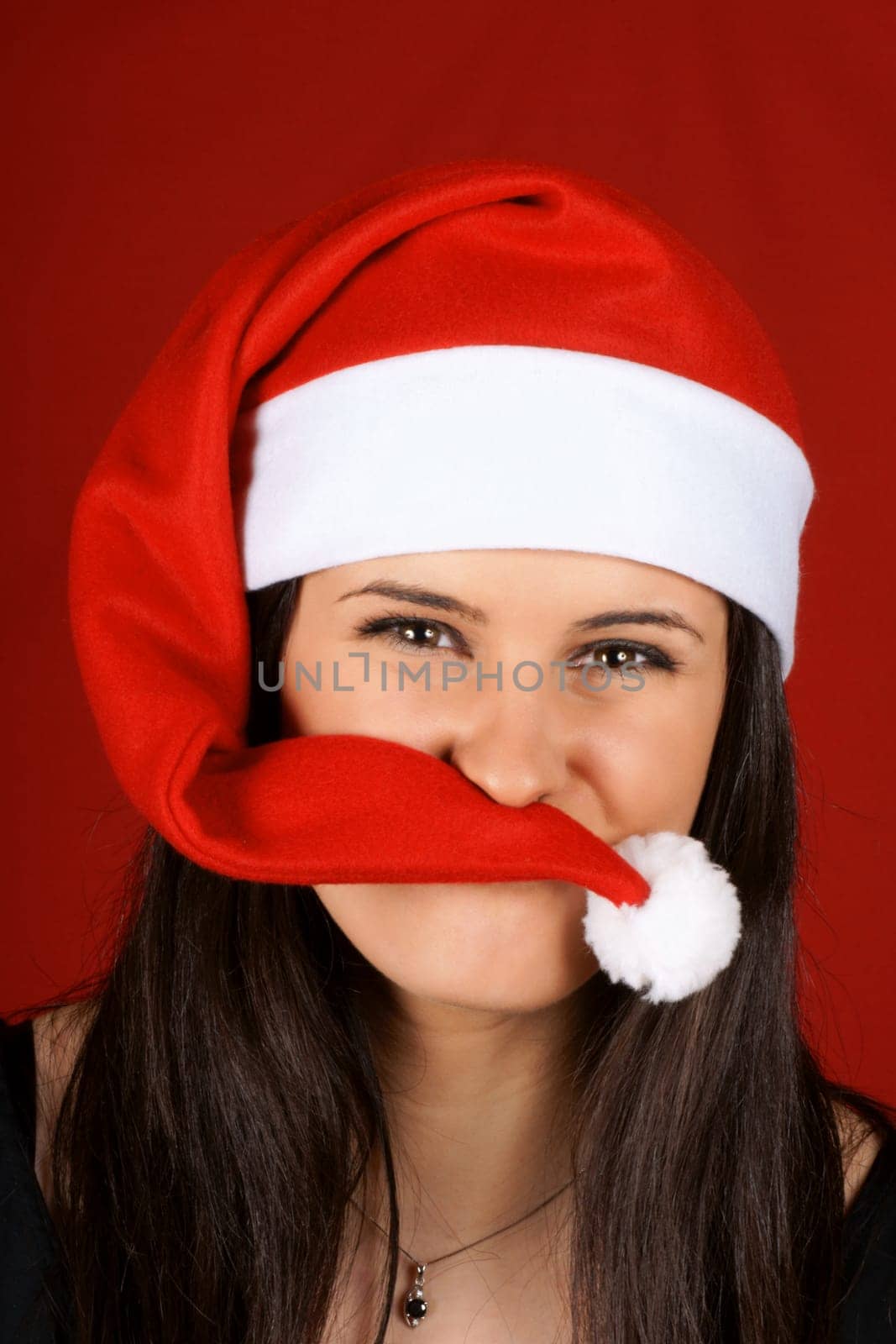 Funny beautiful 18 years old Santa Claus girl looking at camera playing with her red cap.