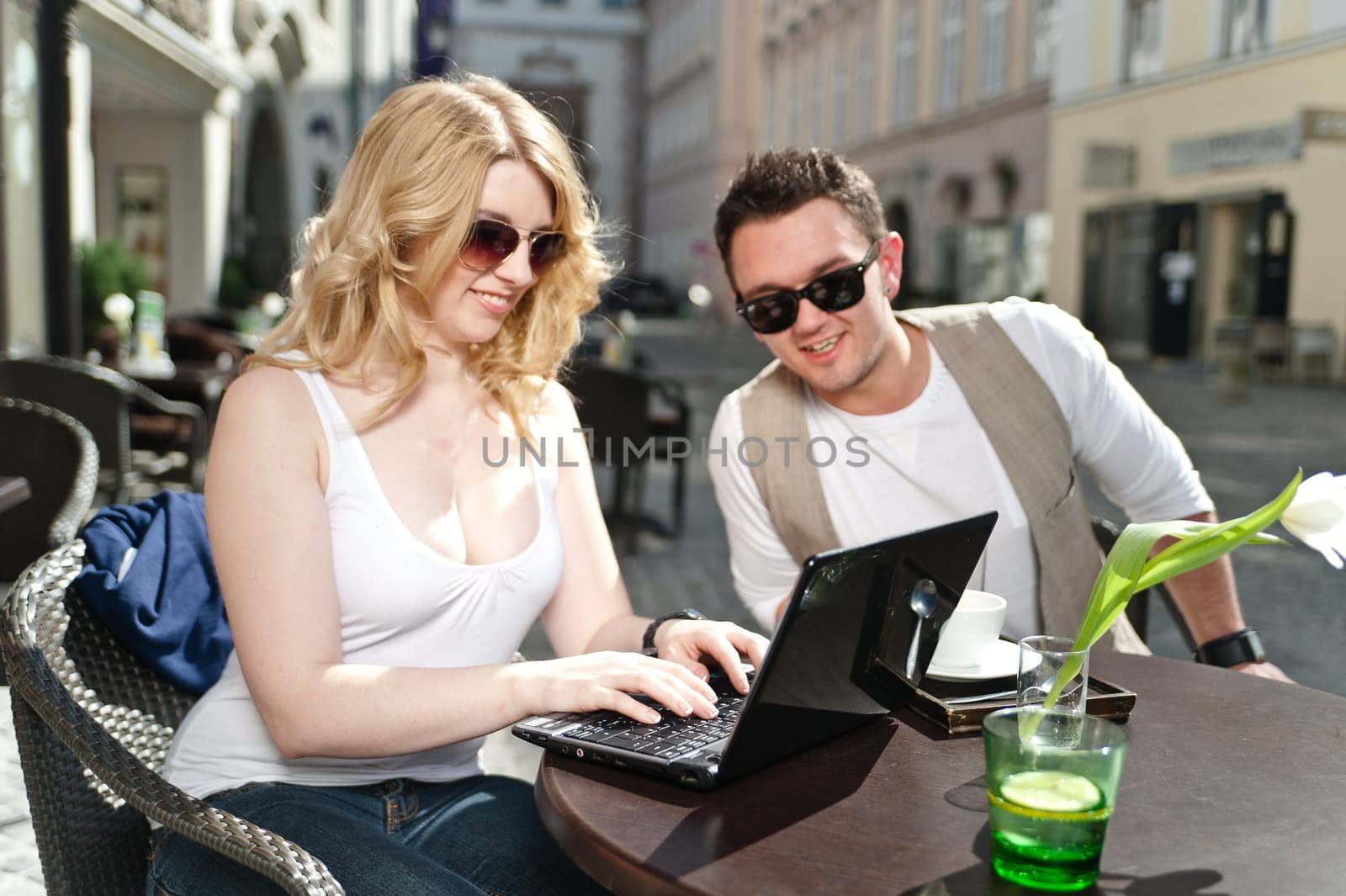 Couple looking at the Laptop, sitting by a table in a Cafe