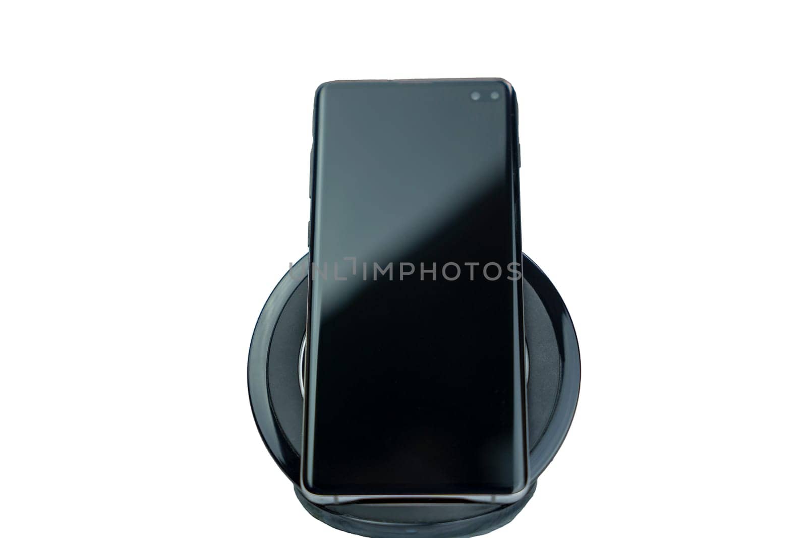 Close-up of a modern black smartphone placed on a wireless charging pad, isolated on a white background, showing technology and convenience.