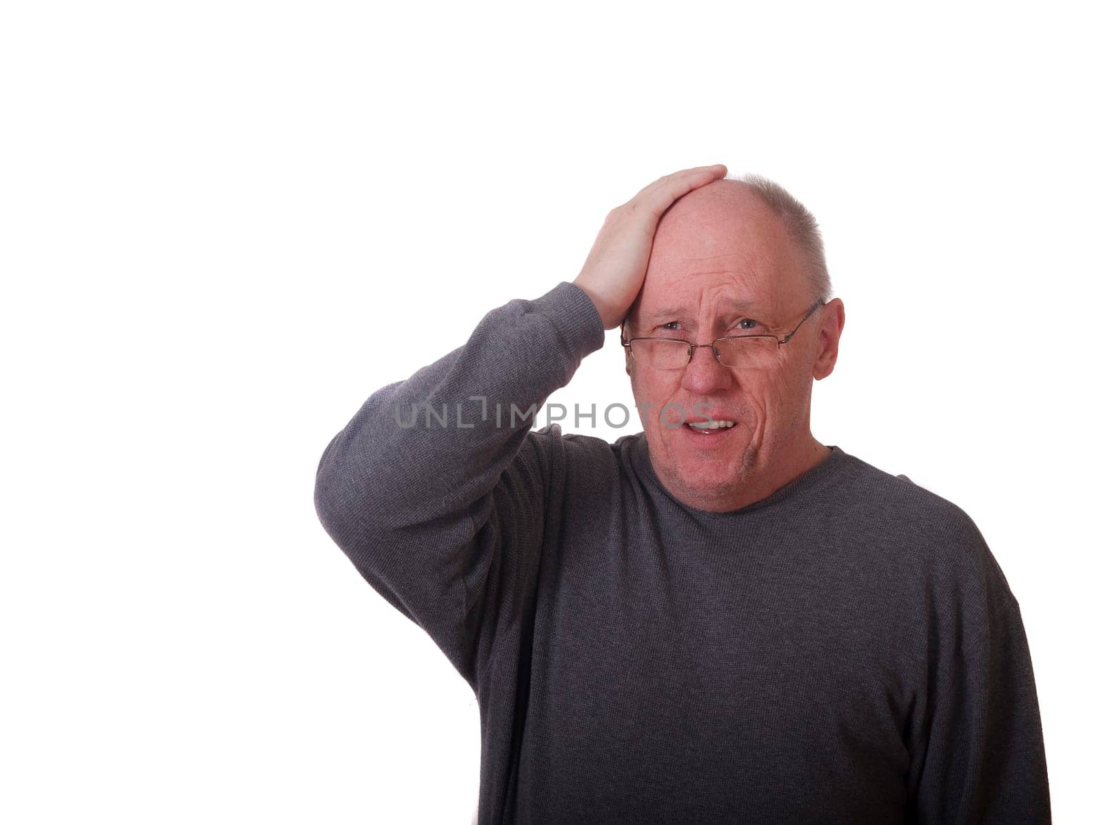 An older man in gray shirt holding his head with pained expression