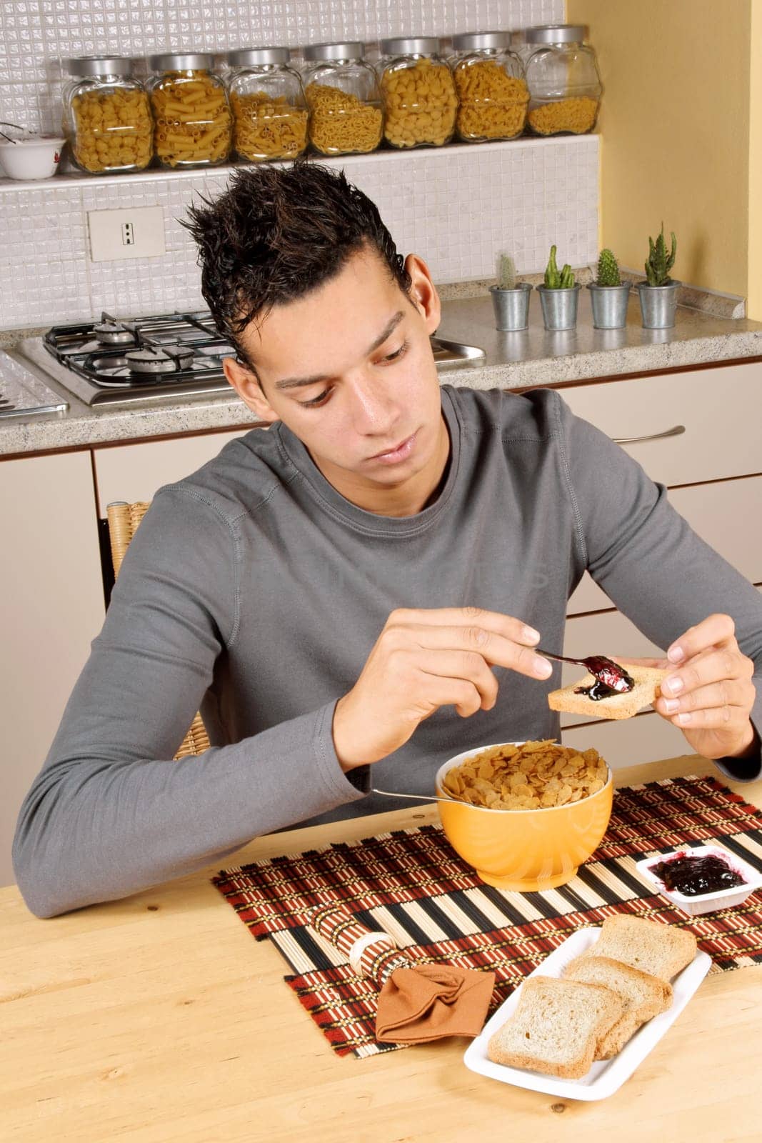 Young brazilian man having breakfast in the kitchen at home.