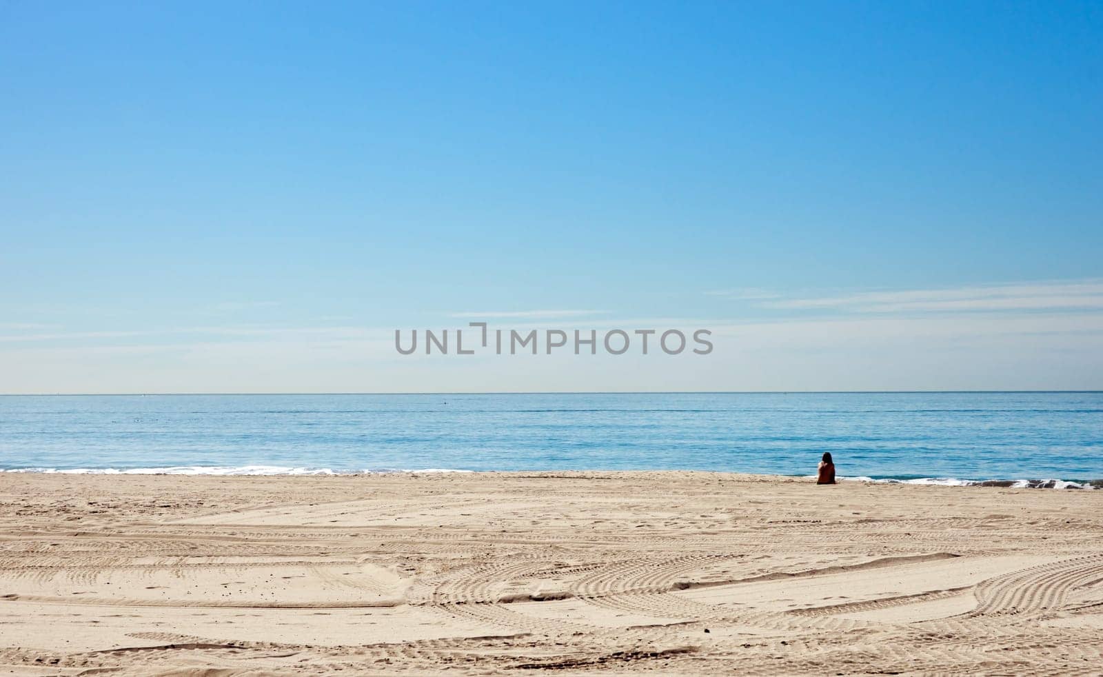 a single woman sits alone on the beach in california