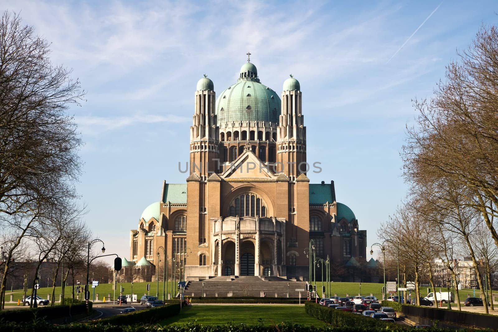 The Basilica of the Sacred Heart in Brussels ranks fifth among the largest churches in the world. The large Art Deco building is catched in the sunlight against a light-blue sky with some clouds.