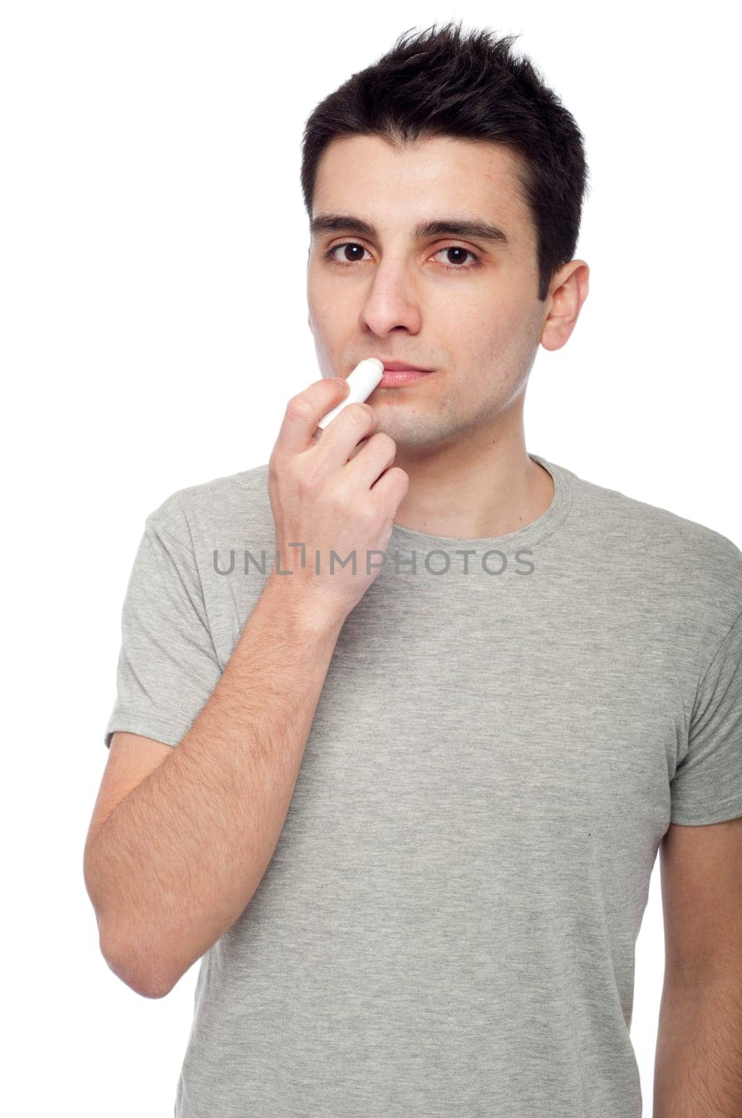 handsome young man applying lip balm (isolated on white background)