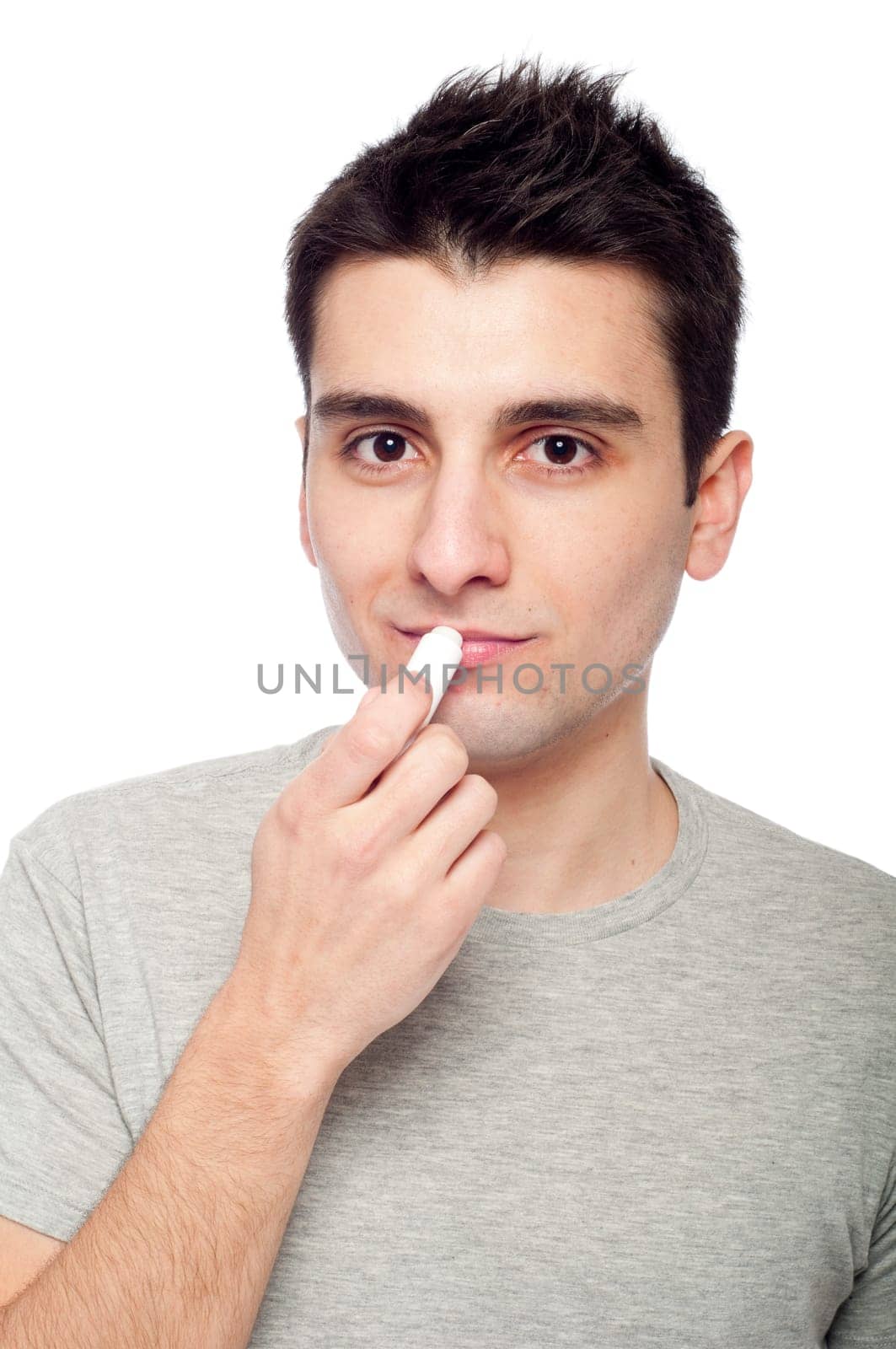 handsome young man applying lip balm (isolated on white background)