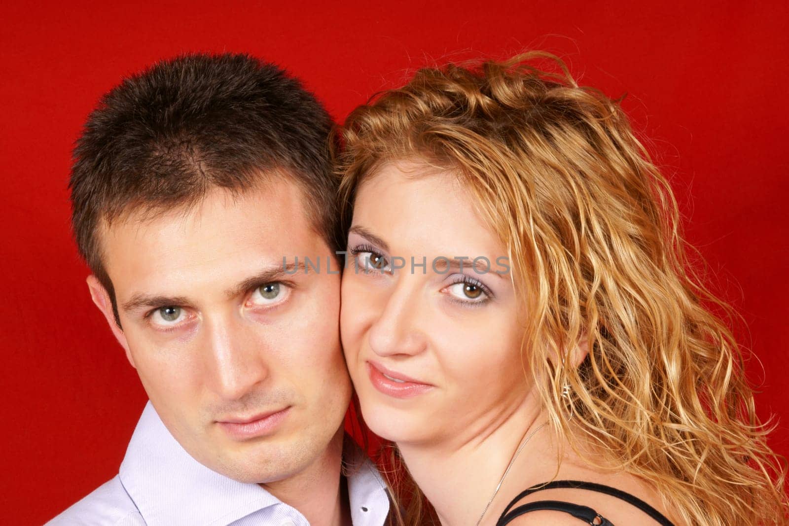 Beautiful young couple in love looking at camera over a red background. Soft focus.
