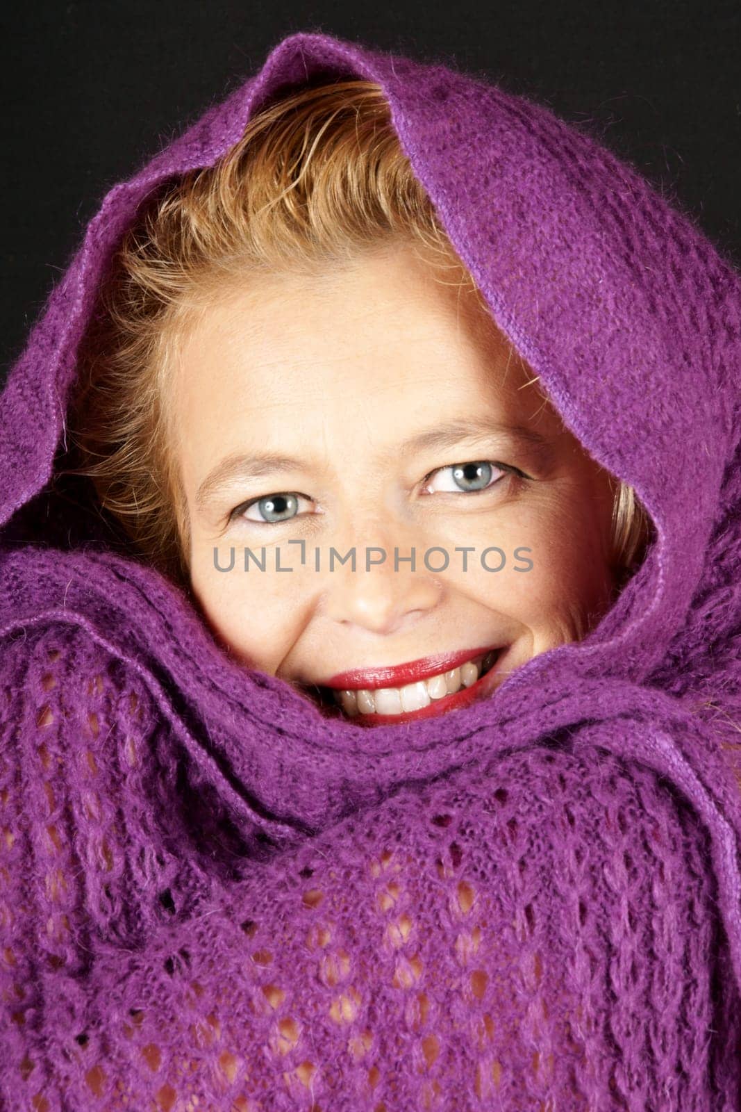 Portrait of a blond woman with purple woolen scarf over black background