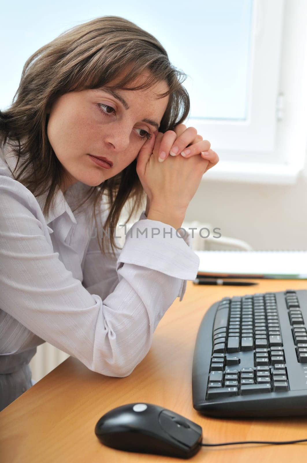Young frustrated and depressed business person (woman) sitting at table with computer