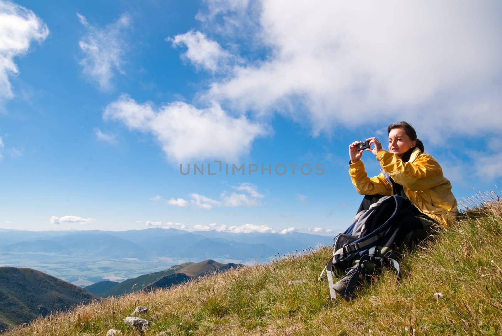 Young person relaxes on hiking in mountains and taking photo with mobile phone