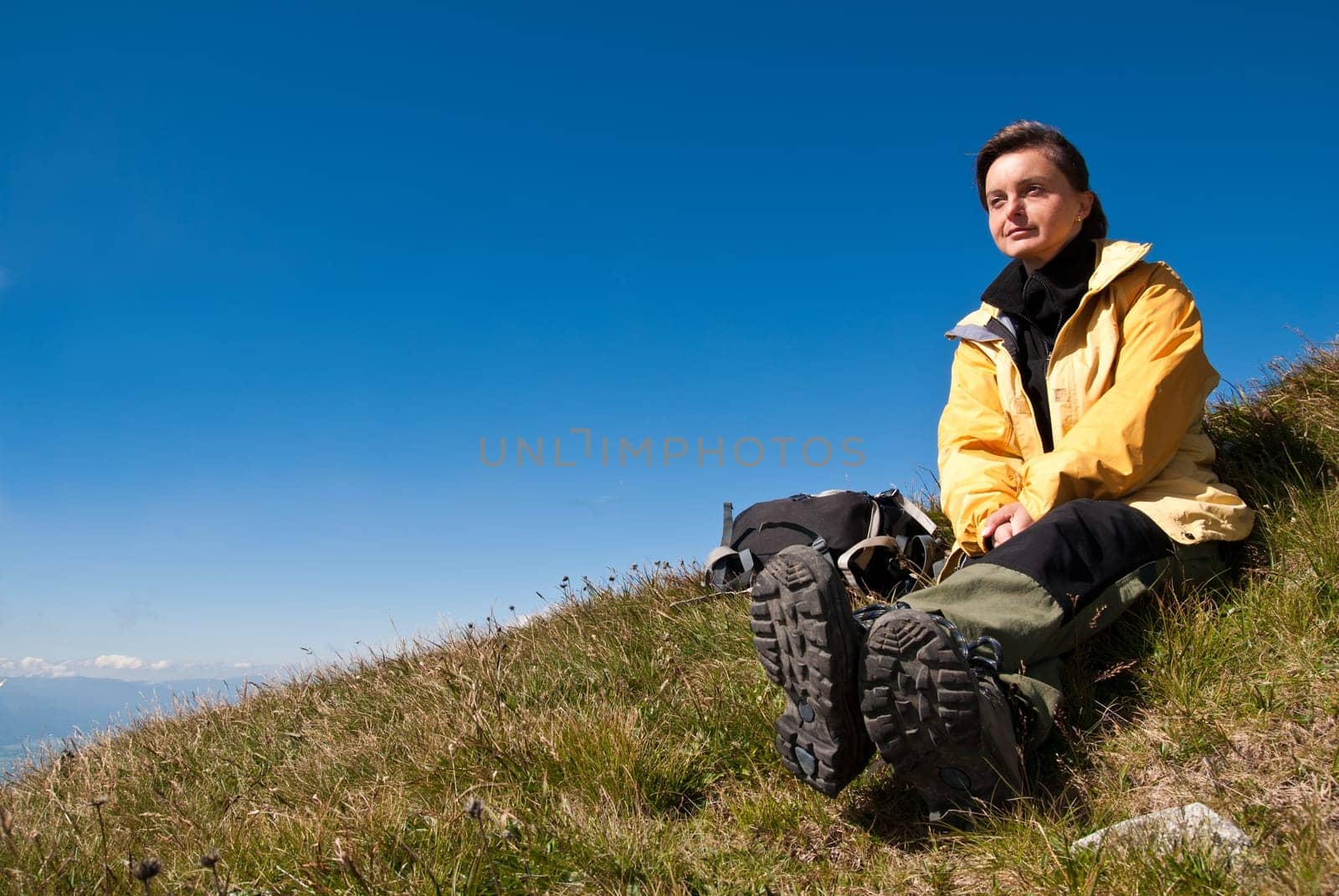 Young person resting on hiking in mountains with clear blue sky
