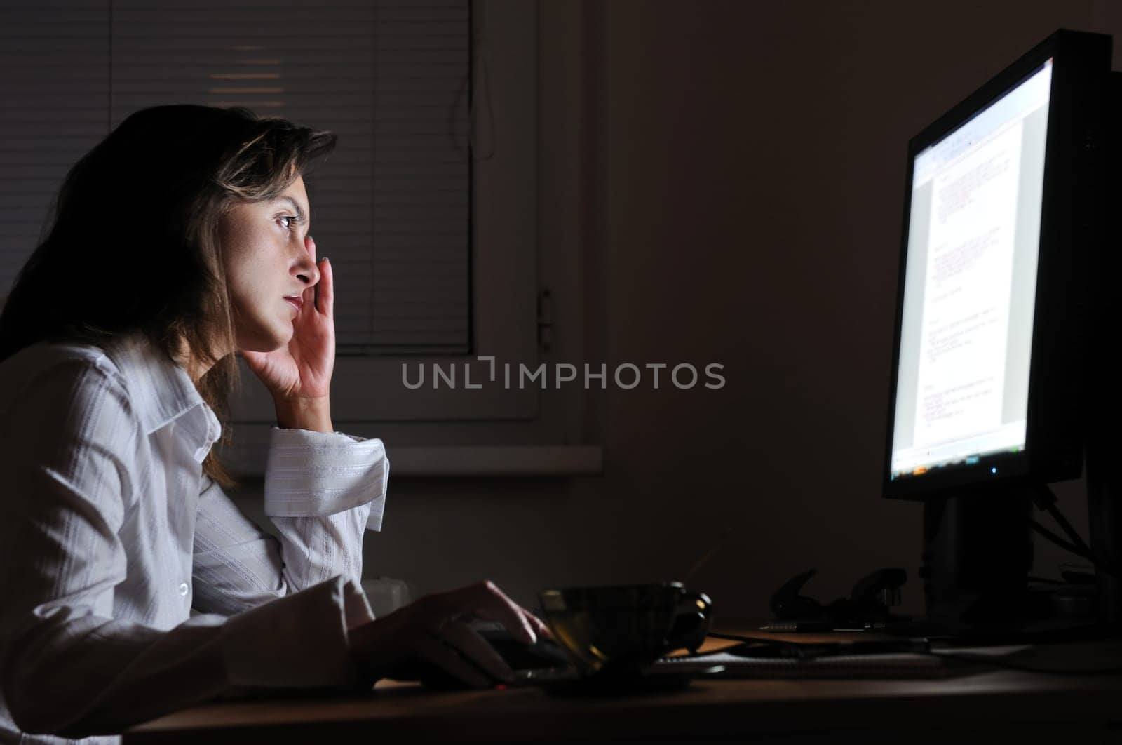 Neck pain - young tired business woman working overtime at computer, night setting