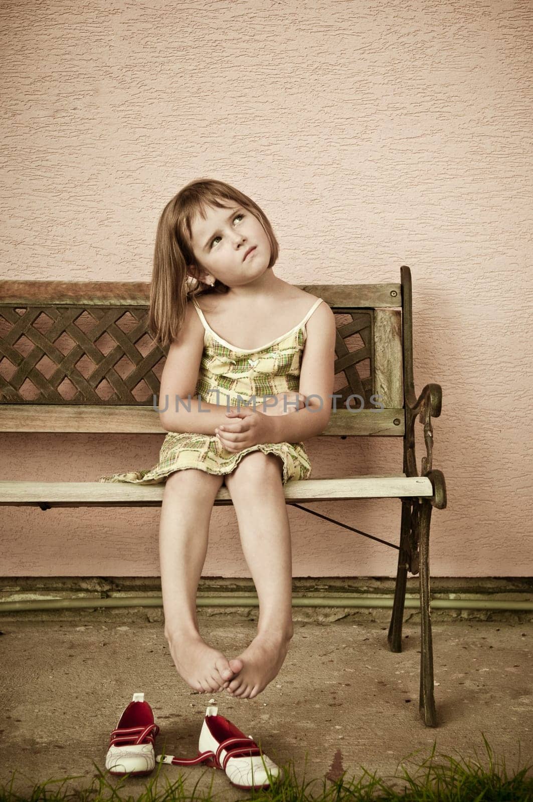 Outdoors portrait of small cute child with hanging legs - sepia tone