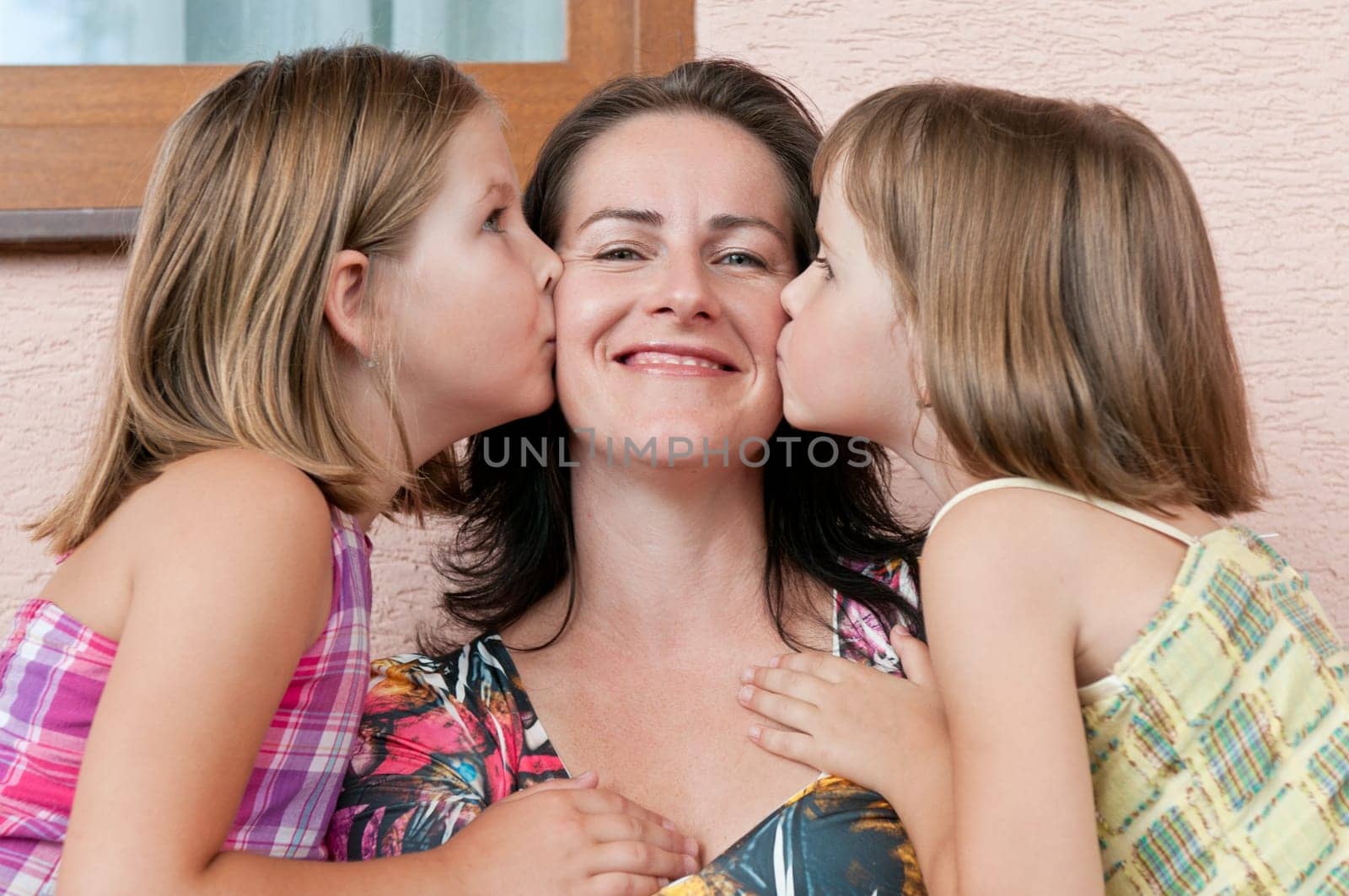 Portrait of children kissing mother with proud and happy expression