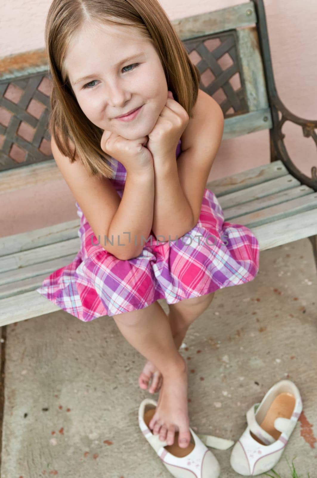 Portrait of cute smiling child sitting on bench - wall in background