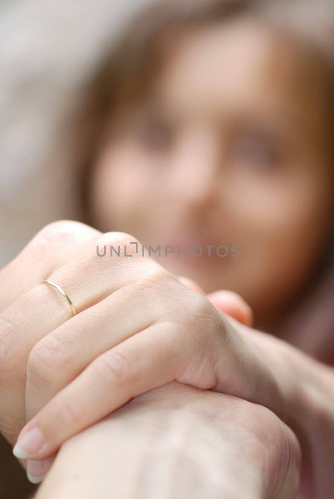 One hand holds another and helps woman whose face is blurred in background