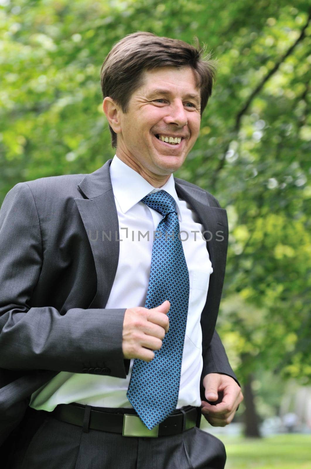 Escape from civilization - smiling senior business man running in park