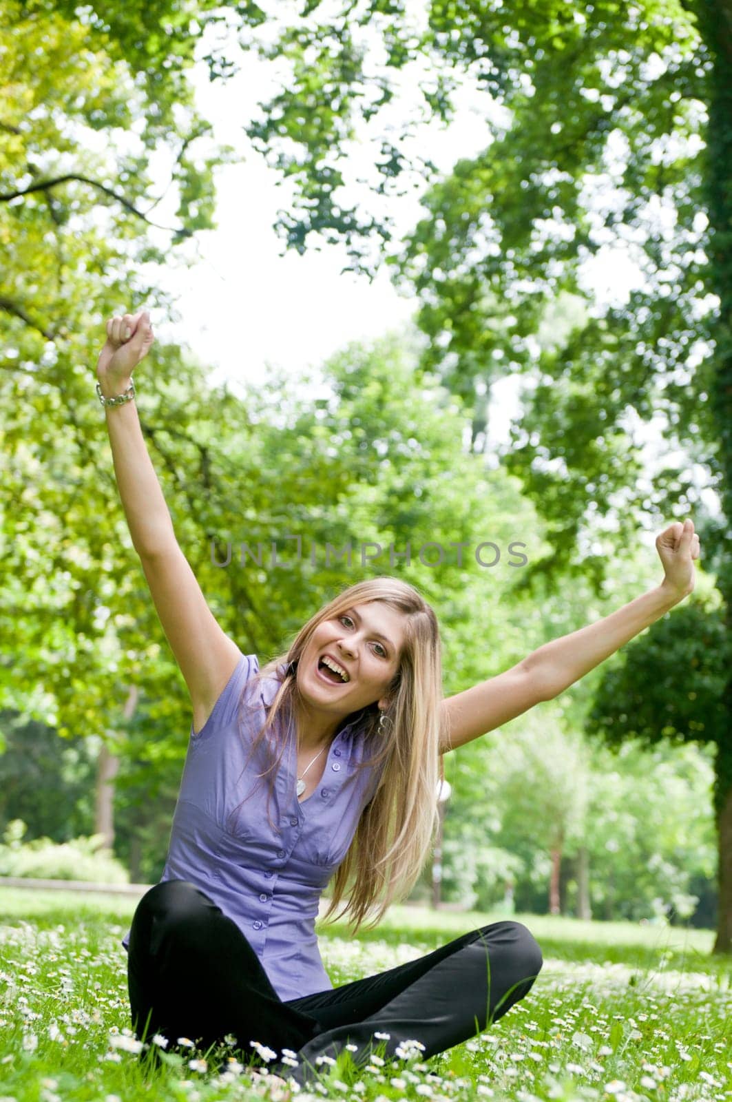 Young happy woman siting in grass with flowers enjoying life