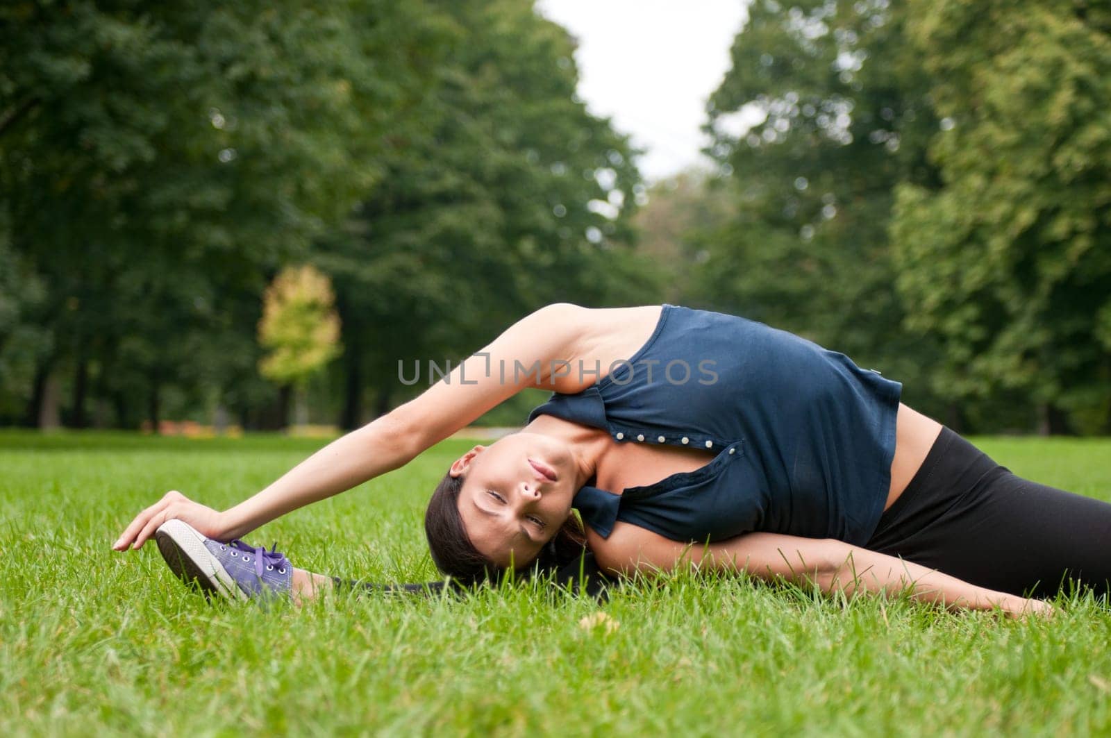 Woman performs stretching before sport in park