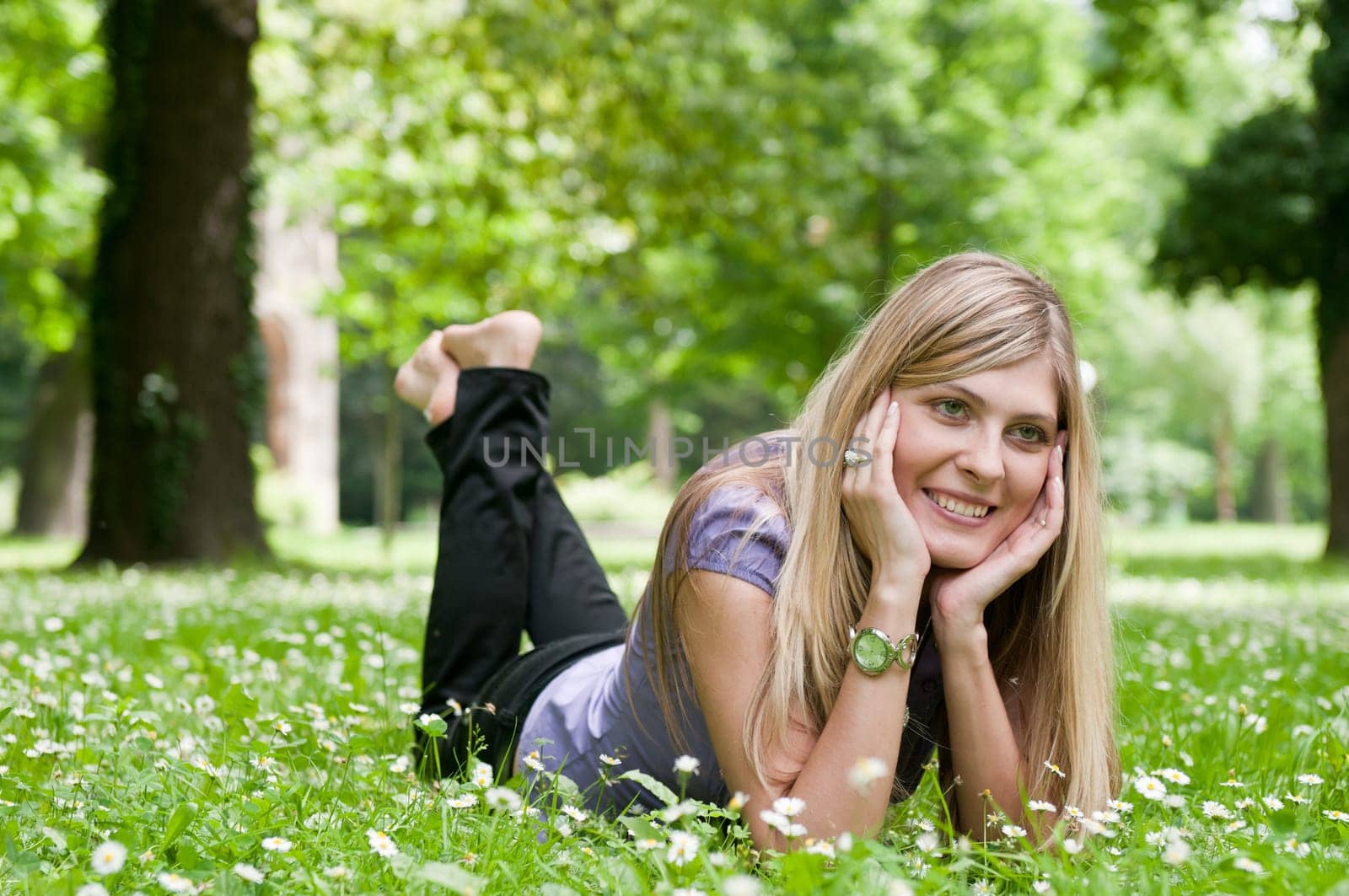 Young smiling woman lying in grass during sunny day (park - outdoors)