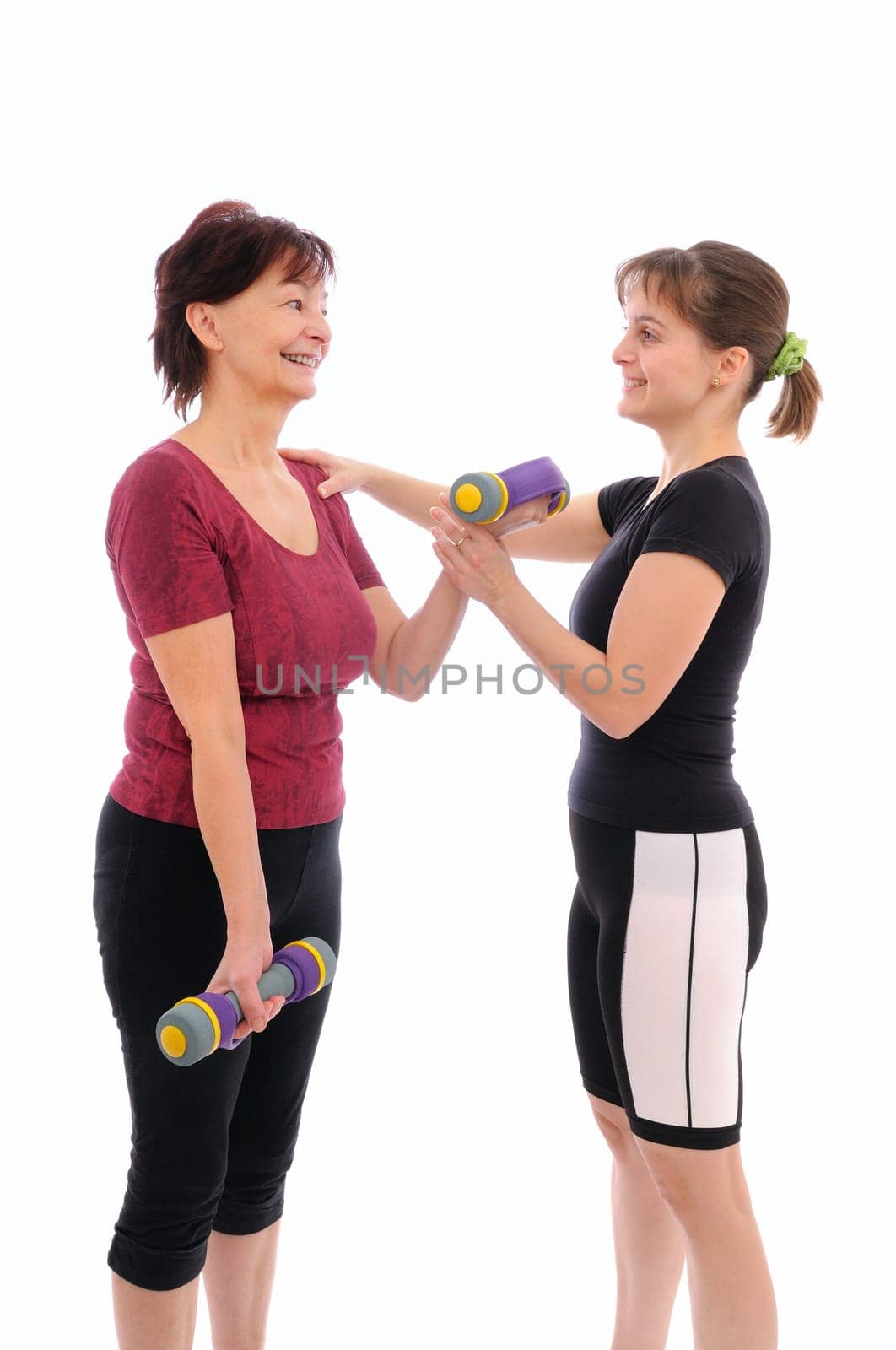 Senior woman  exercising with barbells assisted by trainer