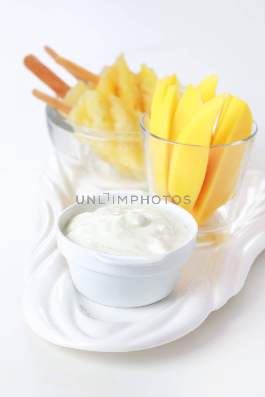 Healthy snack - Pineapple skewer with mango stripes and curd cheese or yogurt