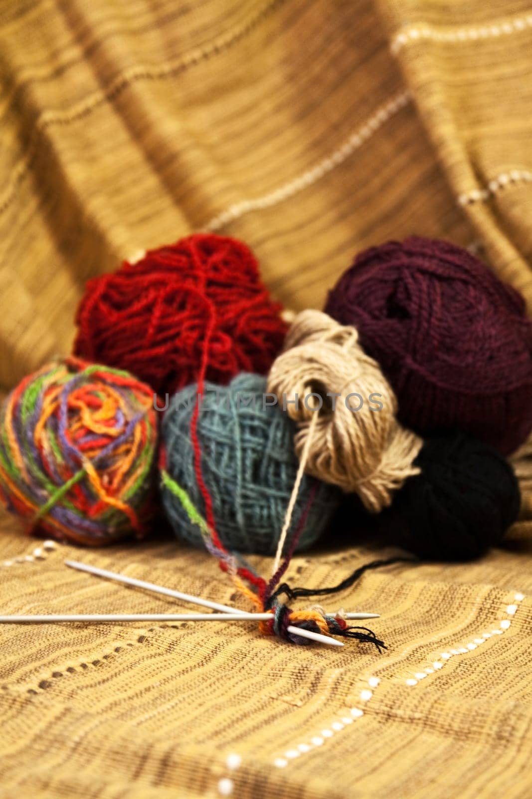 Balls of colored yarn for hand knitting on decorative tablecloth