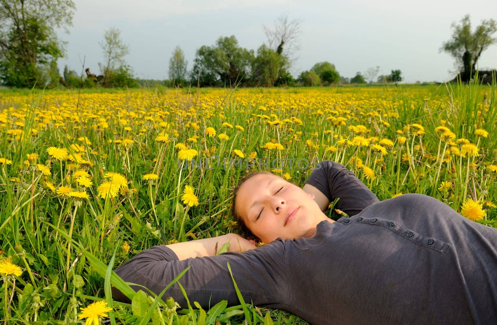 Young woman lying on a flower meadow